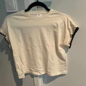 Vit t-shirt med volangärm  - Säljer en vit t-shirt från Zara i storlek 140 (9-10 år). Tröjan har korta ärmar med volangdetalj och mörkblå kant. Perfekt för en avslappnad och trendig look. Tröjan är stor i storlek så skulle säga att den är mer 150 än 140. Skriv till mig för ytterligare frågor😊🩷🫶