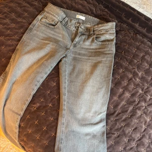 Grå jeansbyxor från Perfect Jeans - Säljer ett par grå jeansbyxor från Perfect Jeans med raka ben och klassisk femficksdesign. Byxorna har dubbla knappar i midjan och en snygg bakficka med lock och knapp. Perfekta till din vardagsstil!