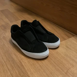 Svarta sneakers från Axel Arigato - Svarta sneakers i mocka från Axel Arigato med vit sula. Lite slitage på undersida häl annars i väldigt gott skick. Priset ej hugget i sten, hör av dig om du har frågor. 
