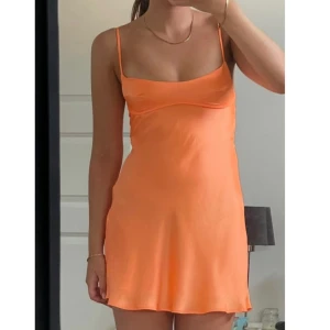 Orange klänning Zara - Orange klänning i satin med smala axelband. Från Zara, använd fåtal gånger. Strl XS