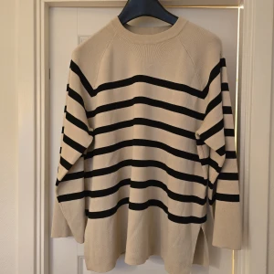 Beige och svart randig stickad tröja från Object - Säljer en beige stickad tröja från Object med svarta horisontella ränder. Tröjan har lång ärm, rund halsringning och en lös passform. Perfekt för en avslappnad och stilren look.