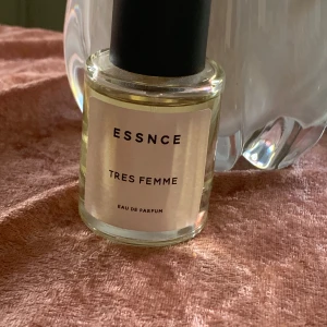 ESSNCE .. Tres Femme .. Eau de Parfum - En elegant parfym från ESSNCE med namnet Tres Femme. Flaskan är rund och genomskinlig med en svart cylinderformad kork och en stilren beige etikett. Innehållet är ljusgult och flaskan rymmer 50 ml. Se bild för hur mycket som är taget ur parfymen. Tillverkad i Frankrike.