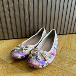 Ballerinaskor Tamaris -  Ballerina från Tamaris med vackert blommigt mönster🌸 Skorna har en rosett framtill och rund tå, använd endast fåtal gånger! Storlek 38