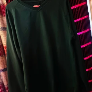 Gamla modellen KV mörkgrön, Vringad häktesteöja.  - Säljer en enkel och stilren mörkgrön höktes tröja med v-ringad hals. På ärmen finns broderade initialer 'KV' vilket inte de senaste upplagorna alls gjort mm. 