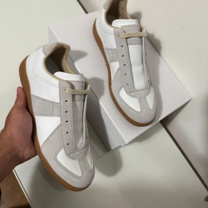 Vita och beige sneakers med gummisula - Säljer ett par stilrena sneakers i vitt och beige med klassisk gummisula. Skorna har paneler i mocka och syntet, rund tå och platt sula. Perfekta för dig som gillar minimalistisk och tidlös design. Hör av dig för snabb affär.