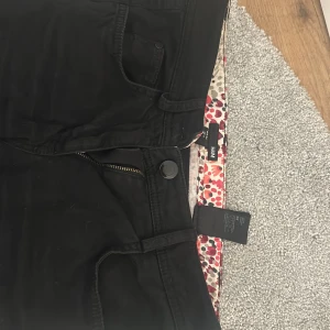 Svarta jeansbyxor från H&M - Svarta jeansbyxor från H&M med klassisk femficksdesign och dragkedja. Byxorna har raka ben och normal passform. finns ett hål vi knäet men det går att sy ihop