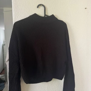 Svart stickad tröja från Divided - Säljer en svart stickad tröja från Divided. Tröjan har en croppad passform, ribbad struktur och långa ärmar. Perfekt för lager-på-lager och enkel att matcha med olika outfits.