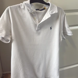 Vit piké från Polo Ralph Lauren - Klassisk vit pikétröja från Polo Ralph Lauren med korta ärmar och broderad logga på bröstet. Köpt från Hede Fashion Outlet i Kungsbacka i present men passade inte mig, endast testad