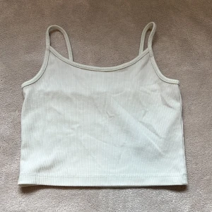 Vit ribbad linnetopp från New Yorker - Säljer en enkel och stilren vit ribbad linnetopp från New Yorker. Toppen har smala axelband och är croppad, perfekt till sommaren. Passar till många olika outfits och är superbekväm.