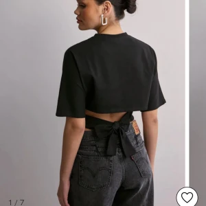 Svart croppad topp med knyt i ryggen - Svart croppad topp med korta ärmar och snygg knytning i ryggen. Perfekt för en trendig och avslappnad stil. Enkel design som passar till mycket.