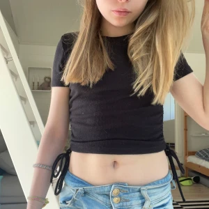 Svart croppad magtröja - Svart croppad topp från Zara med ribbad struktur och korta ärmar. Toppen har knytband i sidorna. Perfekt till jeans eller kjol!!❤️❤️❤️