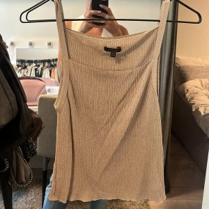 Beige ribbad linnetopp från Massimo Dutti - Säljer en beige ribbad linnetopp från Massimo Dutti. Toppen har smala axelband och en enkel, stilren design som passar perfekt till sommaren. Materialet är mjukt och följsamt för en bekväm känsla.