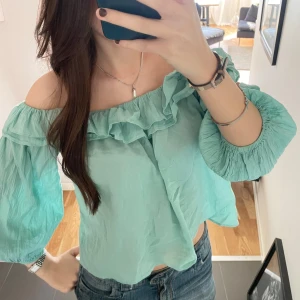Sommar topp - Säljer en mintgrön blus med offshoulder-modell och volangdetalj längs halsringningen. Blusen har trekvartsärmar 🩵🦋