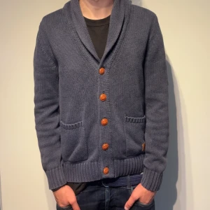 Stickad Cardigan med Fickor - En galet stilren kofta med knappar och fickor framtill - i helt otrolig kvalité! Koftan är i tungt, kvalitativt stickat material. Perfekt för lite kyligare sommarkvällar! Storlek M men passar även S! Har ni några frågor eller funderingar så är det bara att höra av sig!