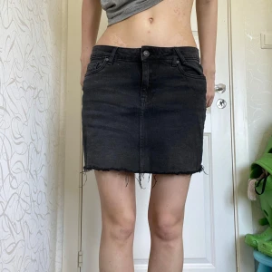 Svart jeans kjol - Säljer en svart jeanskjol från America Today i storlek M. Kjolen har klassisk femficksdesign, rå kant nertill och normal passform. Perfekt för dig som gillar en enkel och stilren look med denimkänsla.
