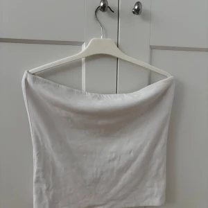 Vit tubtopp från BikBok - Säljer en enkel och stilren vit tubtopp från BikBok. Toppen är ärmlös och har en rak, croppad passform som passar perfekt till sommaren. Tillverkad i mjukt bomullsmaterial för en bekväm känsla. Säljer denna då jag inte längre använder den. Har använt den några gånger😍😍