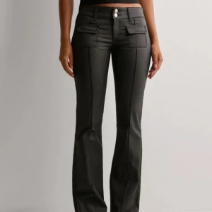 Svarta bootcut byxor med fickor - Snygga svarta byxor med bootcut-passform och dekorativa fickor framtill. Byxorna har hög midja och stängs med två knappar. Perfekta för en trendig och stilren look.