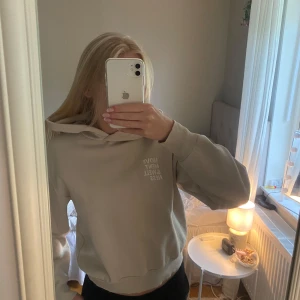 Beige hoodie med tryck - Säljer en beige hoodie med texten 'MOVEMENT & WELLNESS' tryckt i vitt på ryggen och mindre på bröstet. Hoodien har en klassisk passform med huva och ribbade muddar. Perfekt för en avslappnad stil.