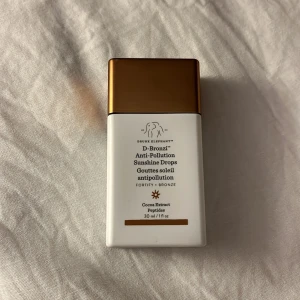 D-Bronzi Anti-Pollution Sunshine Drops - D-Bronzi Anti-Pollution Sunshine Drops från Drunk Elephant ger huden en solkysst bronzig ton. Innehåller kakaoextrakt och peptider. Kommer i en vit plastflaska med bronsfärgat lock, 30 ml. Aldrig använt, som ny. 