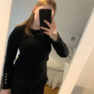Svart stickad tröja - Säljer en svart långärmad tröja med snygga guldfärgade knappar. Säljer då den inte kommer till användning längre. Använd fåtal gånger!💕