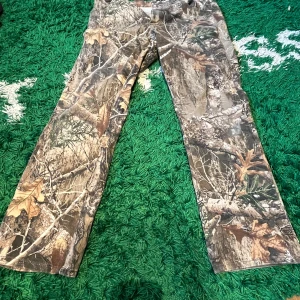 byxor med camouflage från Realtree - Säljer ett par byxor från Realtree med klassiskt camouflage-mönster. Byxorna har raka ben och är perfekta för dig som gillar outdoor eller jakt. Tillverkade i bomull och polyester för extra slitstyrka.