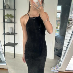 Svart tight ribbad långklänning med smala axelband - Säljer en skitsnygg svart långklänning med smala axelband och ribbad struktur från Gina. Klänningen har en tight passform och är perfekt för alla möjliga olika tillfällen. Har dock blivit lite kort för mig så säljer av den anledningen