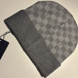 Grå rutig mössa ( helt ny) - Snygg grå mössa med rutigt mönster och bred uppvikt kant. Perfekt för kyliga dagar och passar till de flesta outfits. Klassisk design som funkar året om.