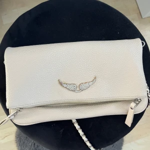 Zadig väska  - .Säljer en Zadig väska köpt här på plick. Det ingår ett kort och ett långt axelband. Märket har små defekter på kanterna men annars i bra skick. Skicka prisförslag