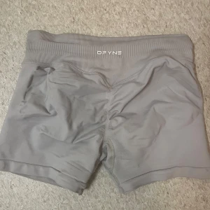 Grå träningsshorts från DFYNE - Gråa shorts från DFYNE, har ett litet hål på framsidan som knappt syns när dom används, storlek S. Ger ett bbl resultat😍(inte vita, ljus gråa) 
