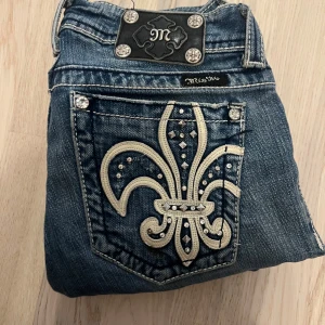 Miss Me Y2K Jeans W27 Bootcut - Säljer ett par blå jeansbyxor från Miss Me med snygga broderade detaljer på bakfickorna. Byxorna har normal passform och klassisk femficksdesign med dekorativa knappar och kontrastsömmar. Jeansen är i w27 och bootcut, skriv för fler frågor! Följare för 5-10% rea