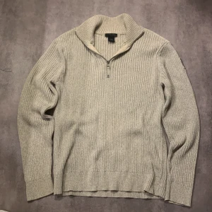 Beige tröja från Calvin Klein  - Säljer en beige, ribbstickad tröja från Calvin Klein Jeans med halv dragkedja och hög krage. Tröjan har lång ärm och logga på ena ärmen. Perfekt för kyligare dagar och enkel att matcha med det mesta. Tröjan är i bra skick och i storlek XL. Bara att höra av sig vid funderingar!