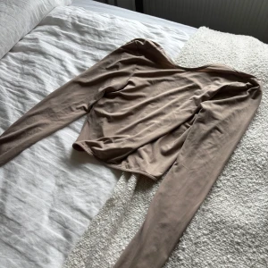 Beige tröja - En helt oanvänd beige tröjan från Nelly med öppen rygg och knytband. I storlek 34 xs. 