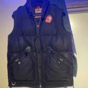 Parajumper Väst - Säljer en svart dunväst från Parajumper.     Storlek L, Inte som nyskick men väldigt bra skick. På bilden ser de ut som ena blixtlåset är trasigt men den är hel hänger bara inuti fickan👍