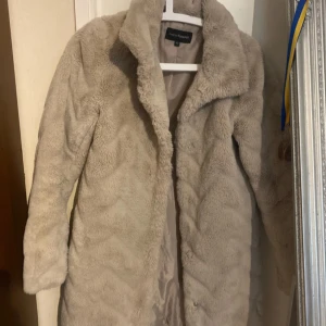 Kappahl pälsjacka  - Säljer en vacker pälsjacka i fint skick. Den är ren och har blivit väl omhändertagen under tiden jag haft den. Jackan saknar några knappar, vilket den gjorde redan när jag fick den, men i övrigt är den i bra skick. Perfekt för dig som gillar vintage och vill ha en unik jacka till garderoben. Säljes i befintligt skick.