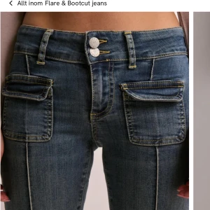 Blå bootcut jeans med fickdetaljer - Snygga blå bootcut jeans med dubbla knappar i midjan och stora fickor framtill. Dessa jeans är mycket populära och är slutsålda. Jag säljer då dom inte passar mig, har aldrig använt. Pris kan diskuteras. Skit snygga!!