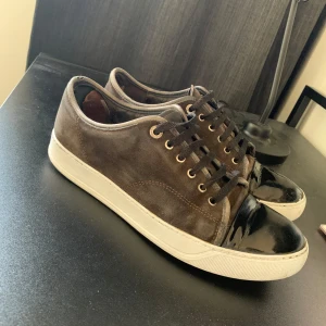 Bruna Lanvins  - Snygga bruna Lanvins i mocka med en glansig svart tå och vita sulor. Skorna har snörning och en stilren design som passar perfekt för en avslappnad look. Nytt pris:5500 kr Mitt pris:1299 