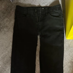 Svarta bootcut jeans - Svarta jeans med bootcut passform och klassisk femficksdesign. Byxorna har låg midja och stängs med dragkedja och knapp. Perfekta för dig som gillar en tidlös look med lite utsvängda ben.