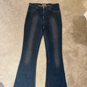 Mörkblå bootcut jeans - Mörkblå jeans med bootcut passform och klassisk femficksdesign. Jeansen har utsvängda ben, vilket ger en retroinspirerad look. Perfekta för dig som gillar en tidlös stil med lite extra attityd.