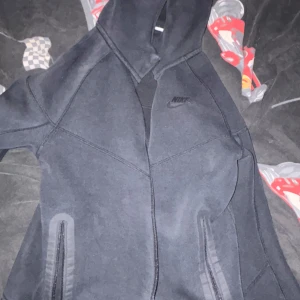 Hej säljer en svart Nike tech tröja -  Säljer en svart Nike tech tröja med en stilig logga på väster bröst, storlek 147-158. Inga märken eller skador, inga tecken på användning. Perfekt för kyliga dager eller om man skulle vilja ha en snygg stilren casual look. Säljer den p.g.a att den inte passar. Pris kan diskuteras Vill gärna bli av med den så snart som möjligt