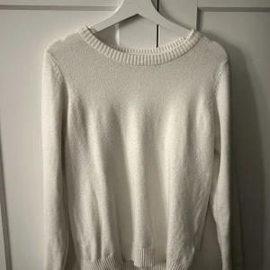 Vit stickad tröja - Säljer en klassisk vit stickad tröja från Vila i storlek M. Tröjan har rund halsringning, långa ärmar och ribbade muddar vid hals, ärmslut och nederkant. Perfekt basplagg för garderoben!