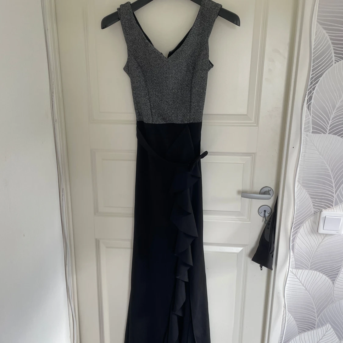 Glittrig långklänning med volang och rosett