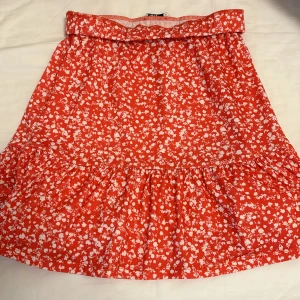 Röd blommig volangkjol från Only - Superfin röd kjol med vita blommor från Only. Kjolen har volang nertill och resår i midjan för en bekväm passform. Perfekt för dig som gillar färg och mönster och super säg till sommaren  eller ute i värmen med en fin solbränna❤️❤️Använd max  en gång, annars oanvänd!