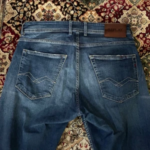 Blå jeansbyxor Replay Grover - Säljer ett par klassiska blå jeansbyxor från Replay, modell Grover. Byxorna har raka ben, fem fickor och snygga detaljer på bakfickorna. Märkespatch i läder baktill i midjan. Perfekta för en avslappnad stil. Byxorna är uppsydda 👍🏻