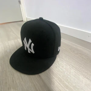 Svart New Era NY keps 59FIFTY - Säljer en svart New Era 59FIFTY keps med klassiskt New York Yankees broderat framtill i vitt. Kepsen har rak skärm och är i modellen fitted, vilket innebär att den inte är justerbar baktill.