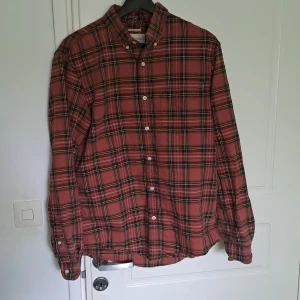 Rutig skjorta från Ralph Lauren - Säljer en röd och svart rutig skjorta från Ralph Lauren Denim & Supply. Skjortan har långa ärmar, klassisk krage och vita knappar framtill. Perfekt för dig som gillar en avslappnad men ändå stilren look.