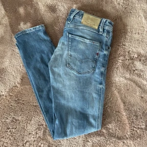 Replay anbass - Säljer ett par ljusblå  Replay anbass med klassisk femficksdesign och knappgylf. Byxorna har en något tvättad look och raka ben. Perfekta för dig som gillar en avslappnad men stilren stil. Har ett hål men syns inte på utsidan. W29 L32
