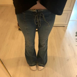 Blå bootcut jeans med snörning i midjan - Säljer ett par blå bootcut jeans med snygg snörning i midjan. Storlek 26😊