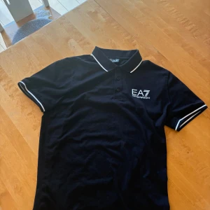 Armani EA7 piké - Snygg Armani EA7 piké tennis tröja i storlek S. Säljes då jag bär S och sitter mer som en M. Har inte används mer än 2-3 gånger och väldigt fin. Köpt på Zalando och fungerande QR kod för äktahetsbevis. Kosta 1600kr ny när den köptes. Tveka inte på att höra av er vid intresse eller om ni har frågor!
