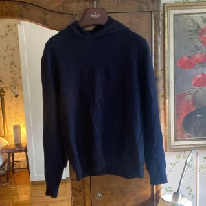 Oscar Jacobson hoodie - Säljer en mörkblå hoodie från Oscar Jacobson i mjuk ull- och kashmirblandning. Tröjan har huva och lång ärm, perfekt för en stilren och avslappnad look. Tillverkad i Italien. Storlek M men passar S. 