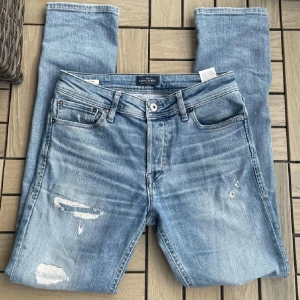 STEAL‼️Ljusa jeans med slitningar från Jack and Jones  - STEAL‼️ Säljer ett par jack and Jones jeans med slitningar, Jeansen är iprincip nya. Använda endast en gång. Väldigt unik modell, svåra att få tag på😃jeansen är slim fit👍